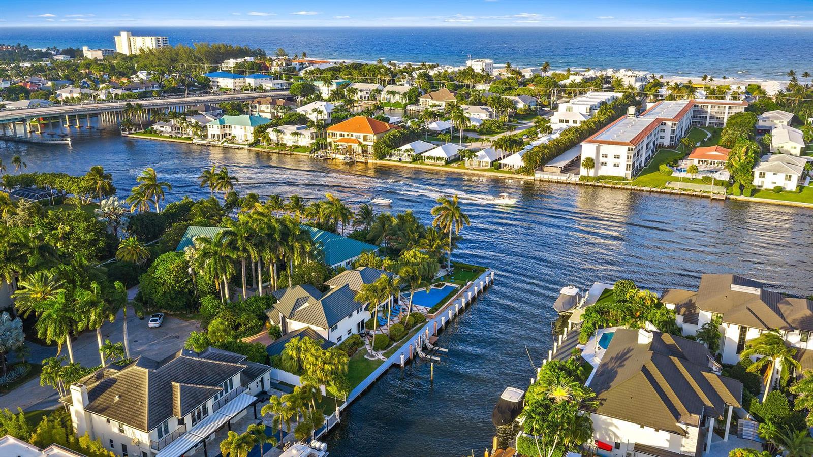 An aerial view shows waterfront homes with pools along a canal leading to the ocean — 964 Eve Street, Delray Beach FL 33483, DELRAY BEACH, FL
