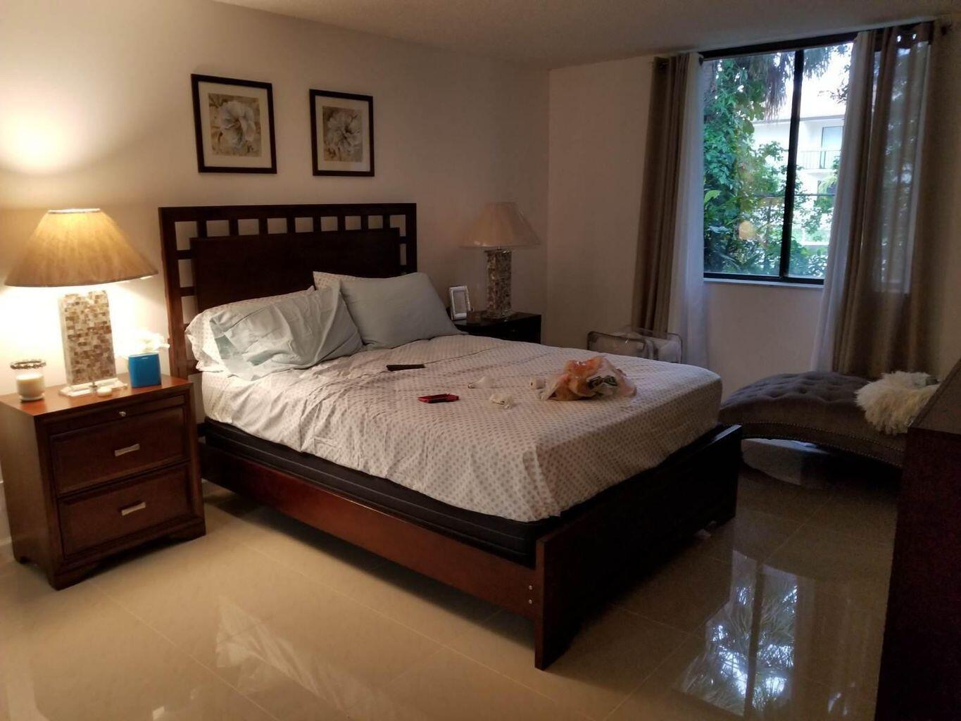 A bedroom with a dark wood bed frame, two nightstands, and a window with curtains — 733 SE 1st Way # 105, Deerfield Beach FL 33441, DEERFIELD BEACH, FL