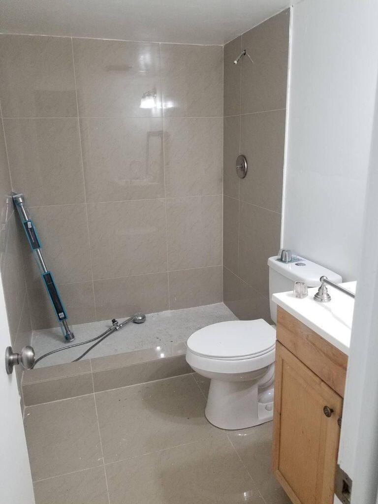 A bathroom with beige tiled walls, a walk-in shower area, a toilet, and a vanity — 733 SE 1st Way # 105, Deerfield Beach FL 33441, DEERFIELD BEACH, FL