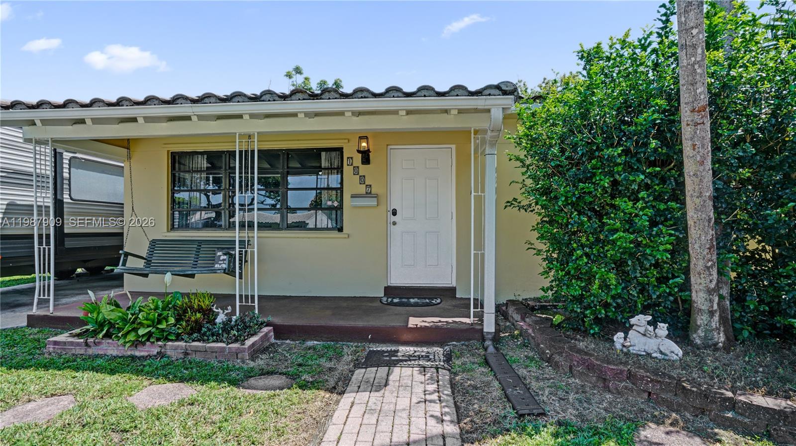 The exterior of a single-story house features a front porch with a swing and walkway — 1007 N 31st Rd, Hollywood FL 33021, HOLLYWOOD, FL