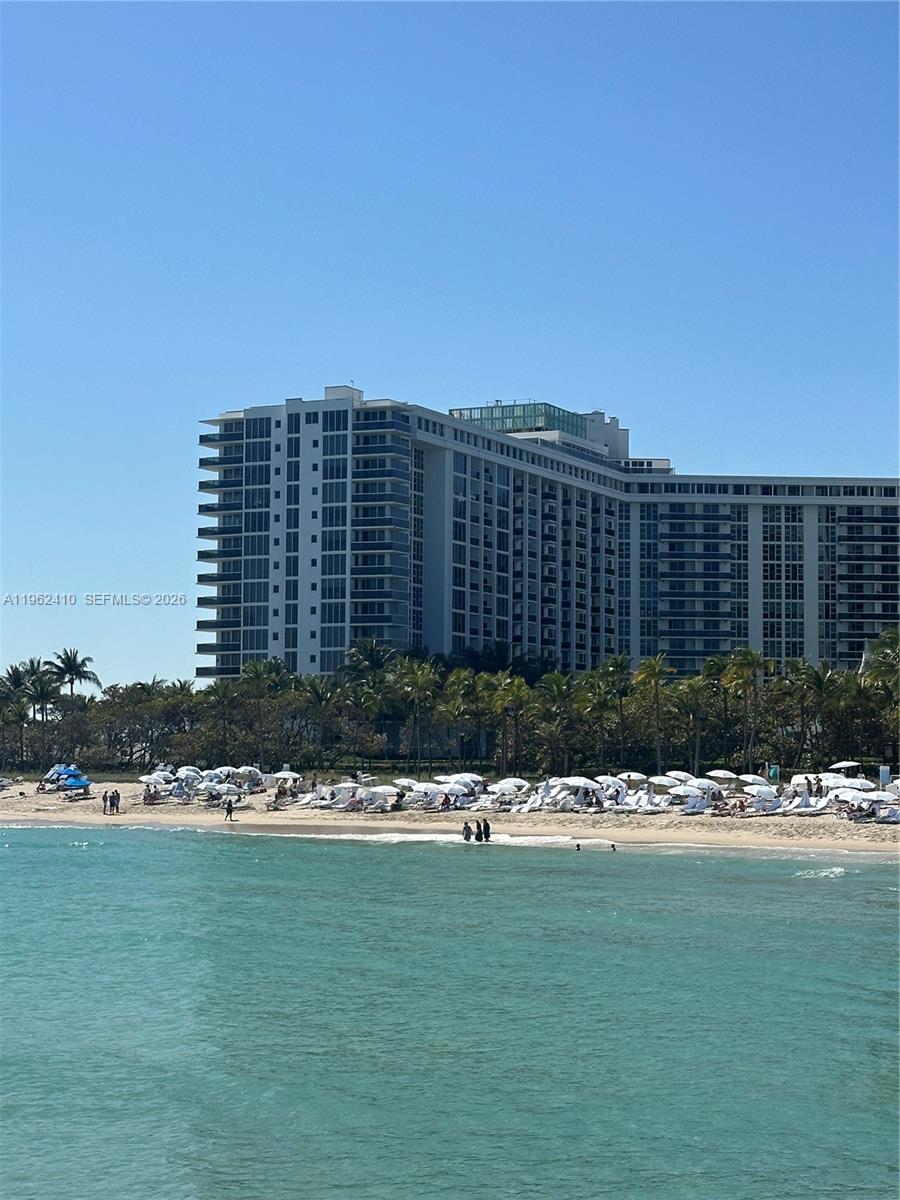 A large multi-story apartment building stands behind a sandy beach filled with white umbrellas — 10275 Collins Ave # 1402, Bal Harbour FL 33154, BAL HARBOUR, FL