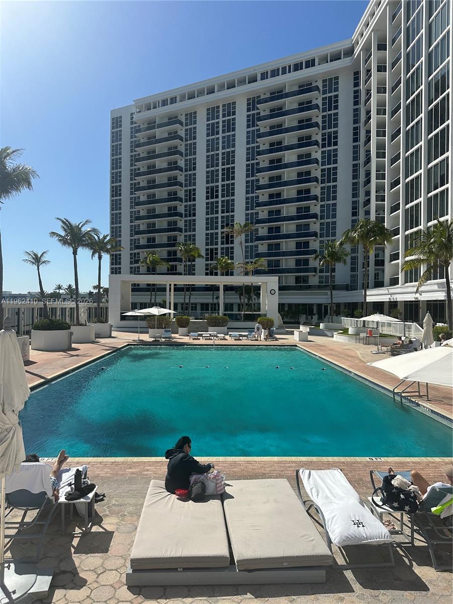 A large swimming pool sits in front of a tall, multi-story white residential building — 10275 Collins Ave # 1402, Bal Harbour FL 33154, BAL HARBOUR, FL