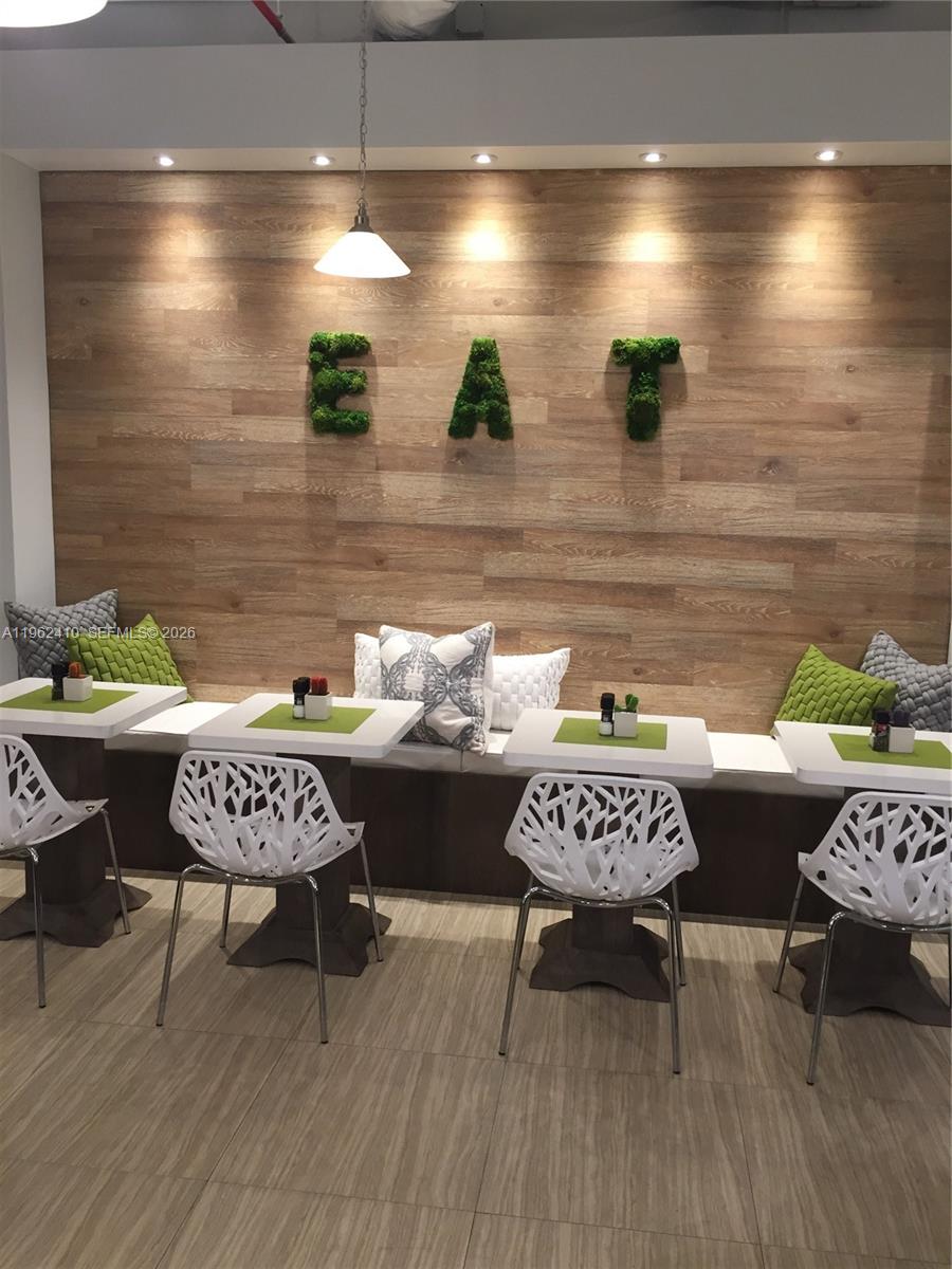 A dining area features a wood-paneled wall with moss letters spelling EAT above booth seating — 10275 Collins Ave # 1402, Bal Harbour FL 33154, BAL HARBOUR, FL