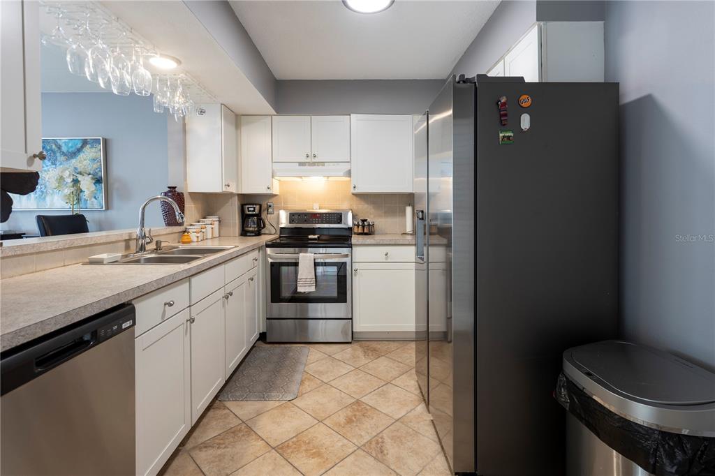 A kitchen features white cabinets, stainless steel appliances, a tiled floor, and a breakfast bar — 5825 PUERTA DEL SOL BOULEVARD S UNIT 265, ST PETERSBURG, FL