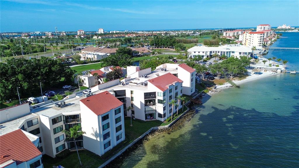 An aerial view of a multi-story waterfront apartment complex with red roofs along the coast — 5825 PUERTA DEL SOL BOULEVARD S UNIT 265, ST PETERSBURG, FL