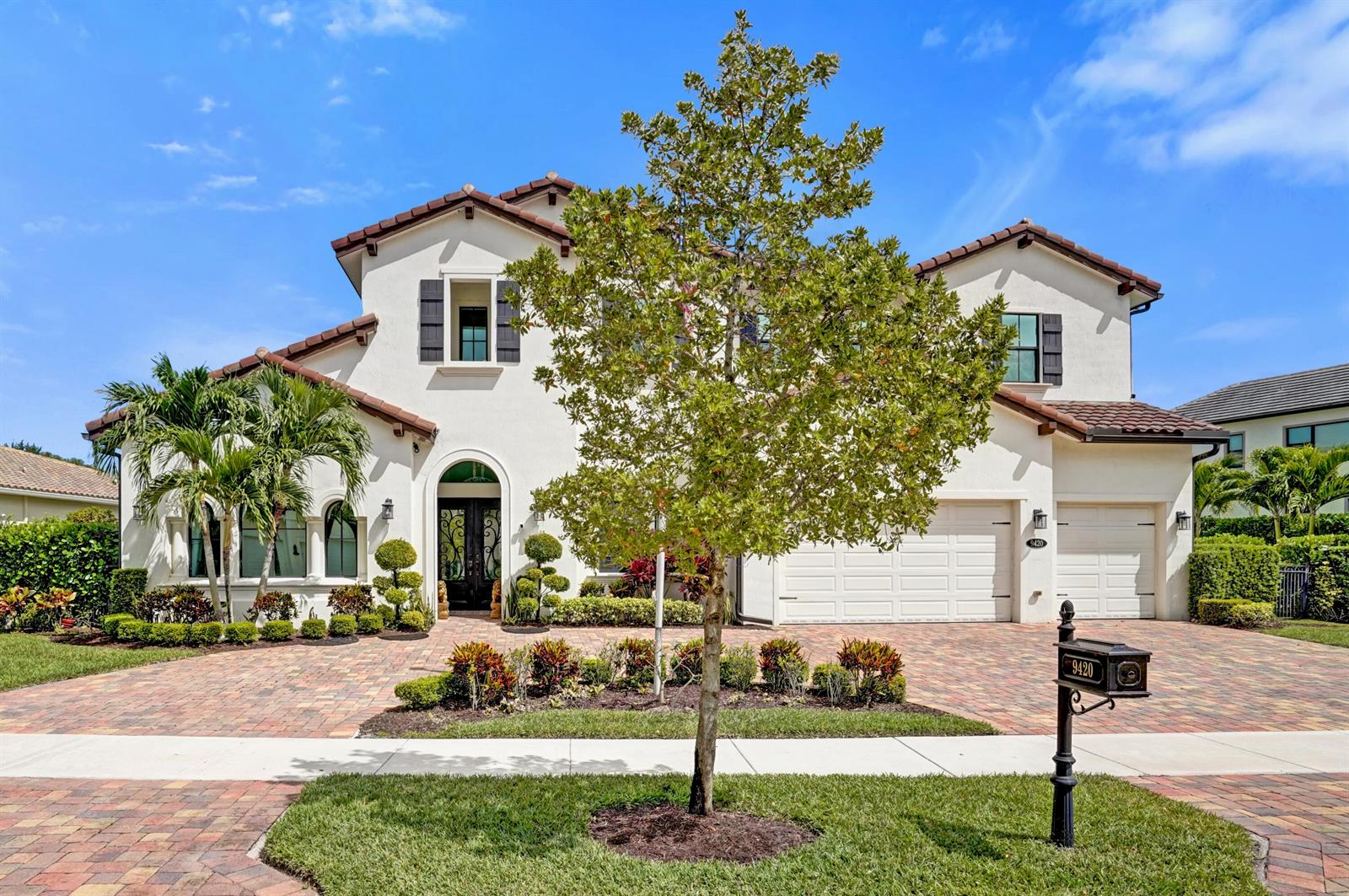 A two-story stucco house with a tile roof, arched entryway, and a brick paver driveway — 9420 Grand Prix Lane, Boynton Beach FL 33472, BOYNTON BEACH, FL