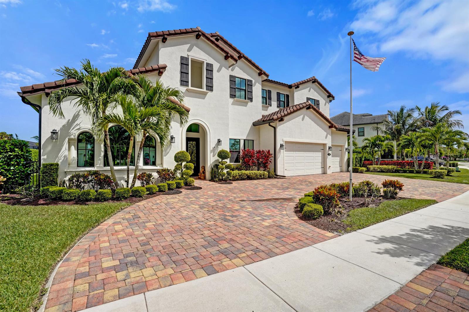 A two-story stucco house with a paver driveway, palm trees, and an American flag — 9420 Grand Prix Lane, Boynton Beach FL 33472, BOYNTON BEACH, FL