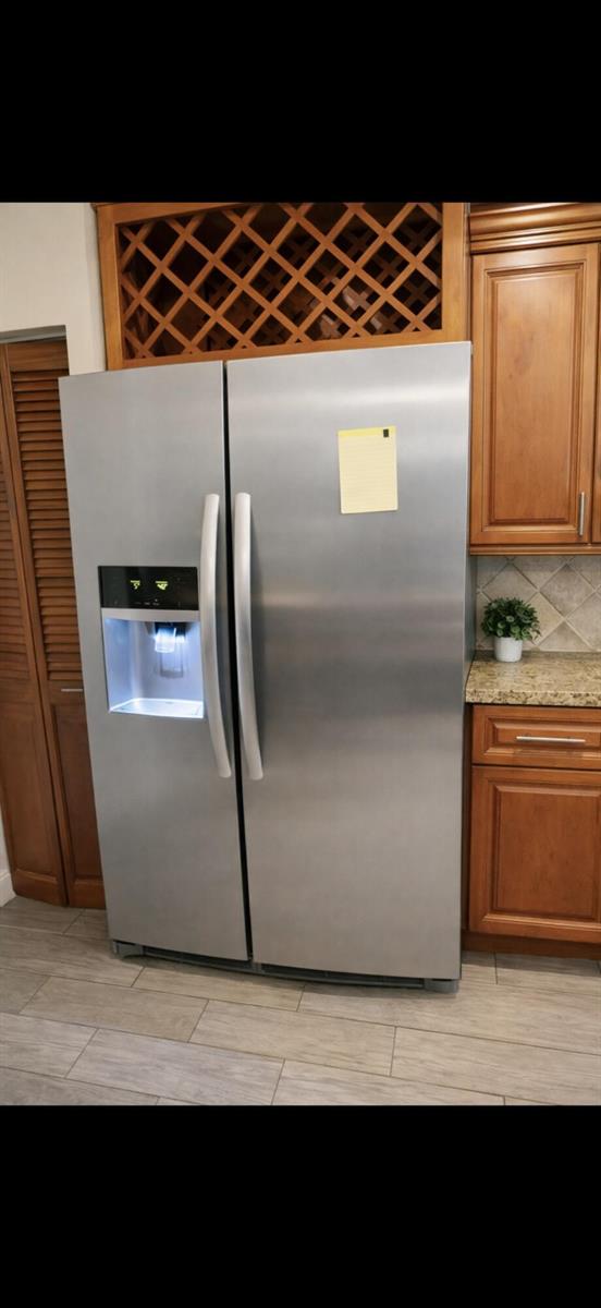 A stainless steel side-by-side refrigerator is positioned in a kitchen with wood cabinetry — 223 Foxtail Drive # C, FL 33415, FL