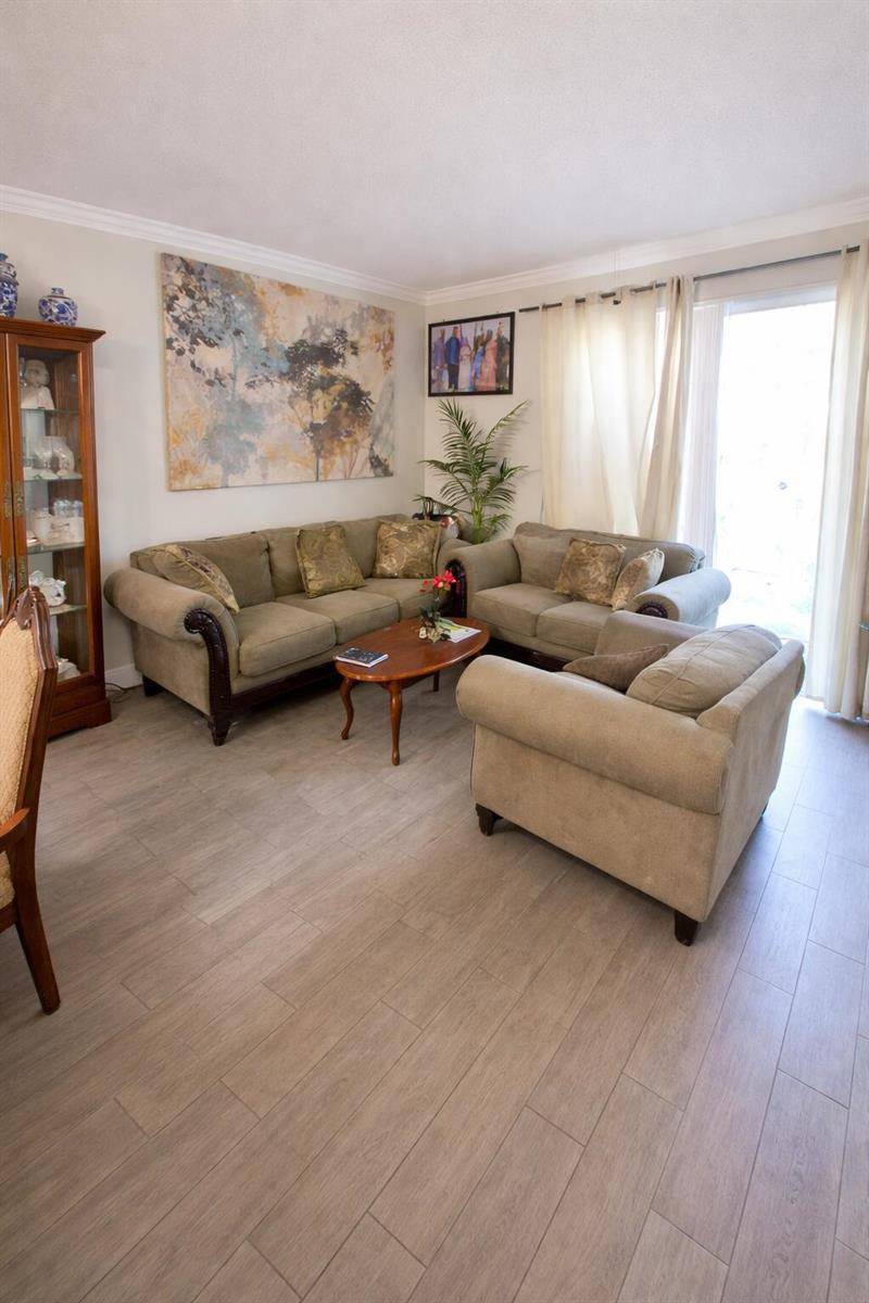 A living room features light wood-look flooring, a beige sofa set, and a large painting — 223 Foxtail Drive # C, FL 33415, FL