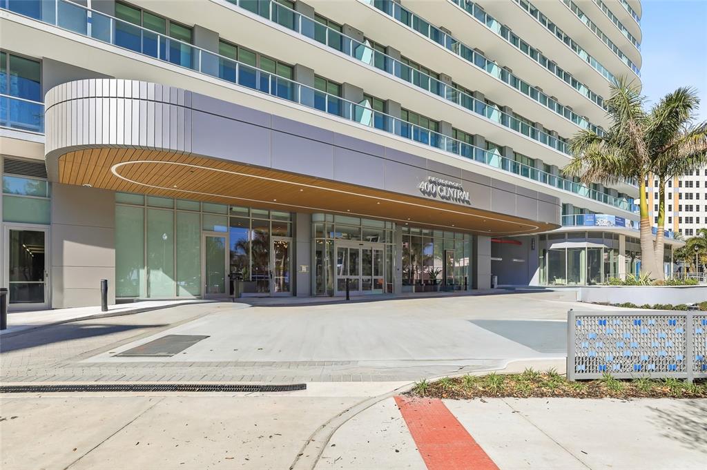 The exterior of a modern multi-story residential building features a covered entrance and glass facade — 400 CENTRAL AVENUE UNIT 505, ST PETERSBURG, FL