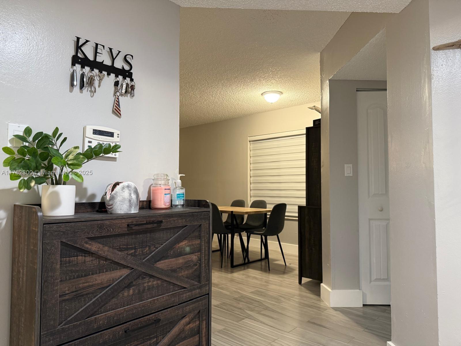 A dark wood shoe cabinet sits in a hallway leading to a dining area — 9121 SW 138th Pl # 9121, Miami FL 33186, MIAMI, FL