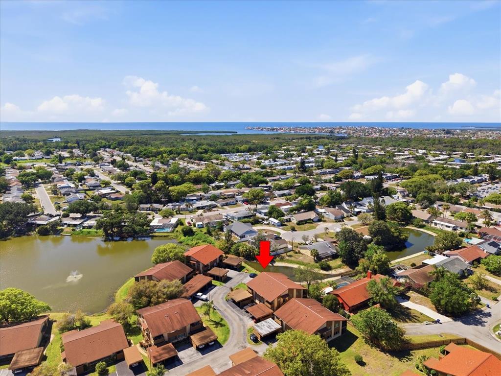 An aerial view shows a residential complex with brown roofs near a small lake — 4034 DAVIT DRIVE UNIT 4034, NEW PORT RICHEY, FL