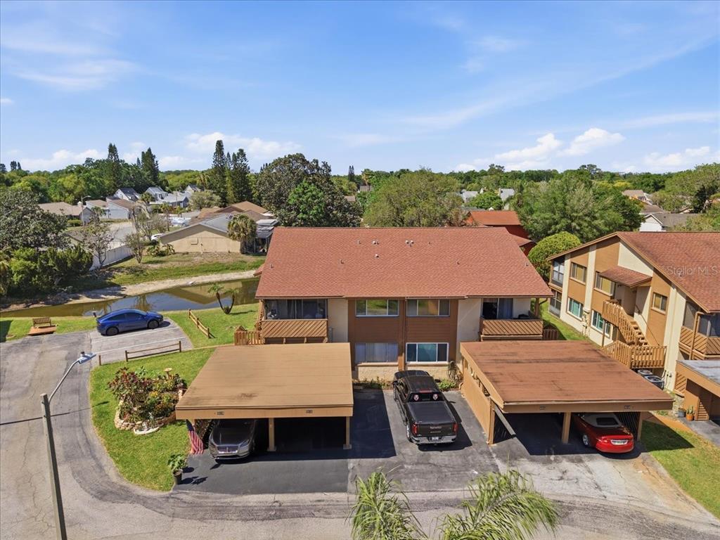 An aerial view of a two-story apartment building with attached carports and a small pond — 4034 DAVIT DRIVE UNIT 4034, NEW PORT RICHEY, FL