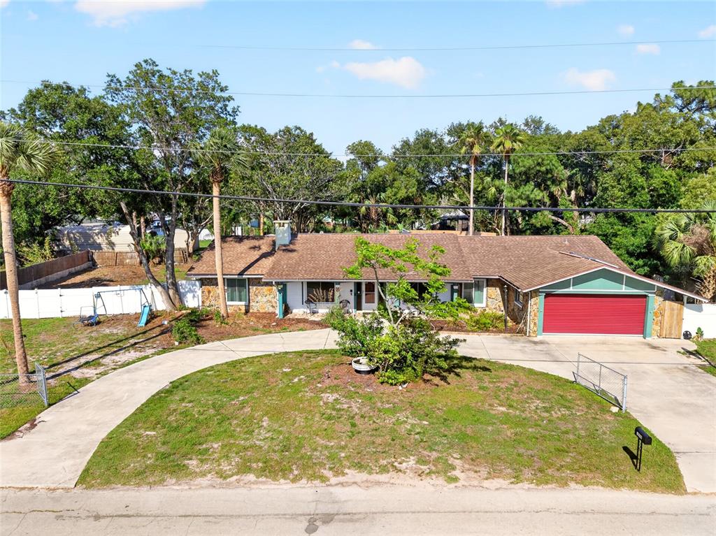 An exterior view of a single-story house with a red garage door and circular driveway — 16206 SEA PINES DRIVE, HUDSON, FL