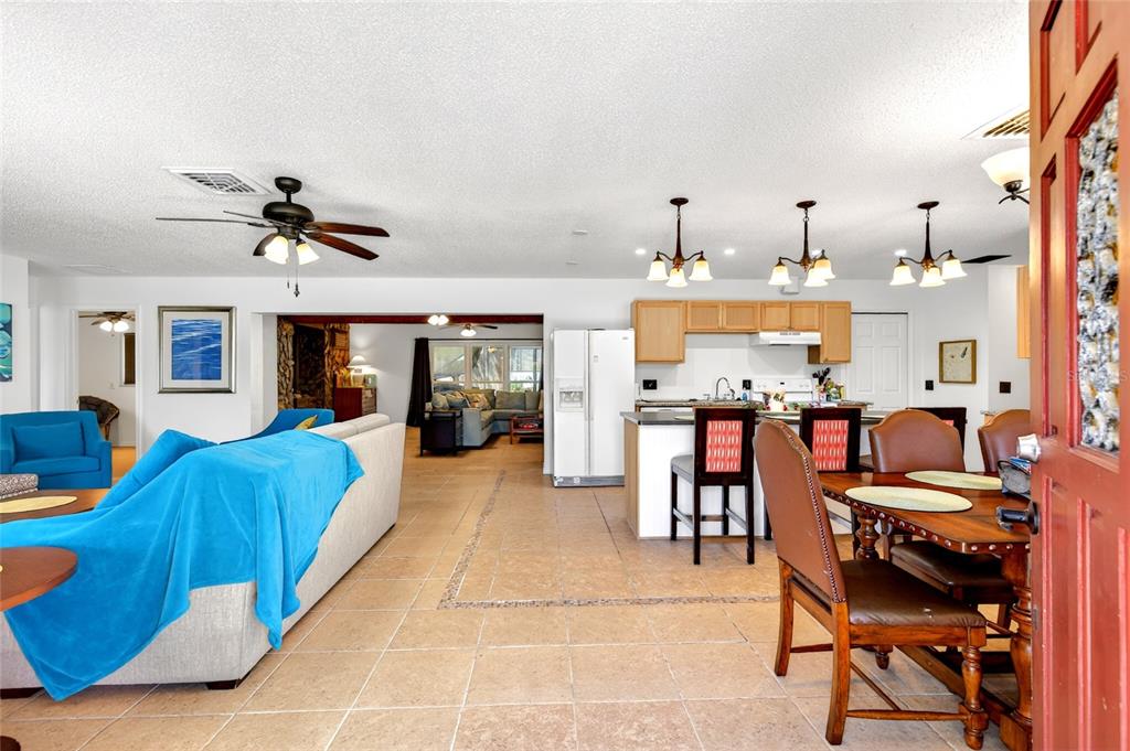 An open-concept living and dining area features tile flooring, a kitchen island, and ceiling fans — 16206 SEA PINES DRIVE, HUDSON, FL
