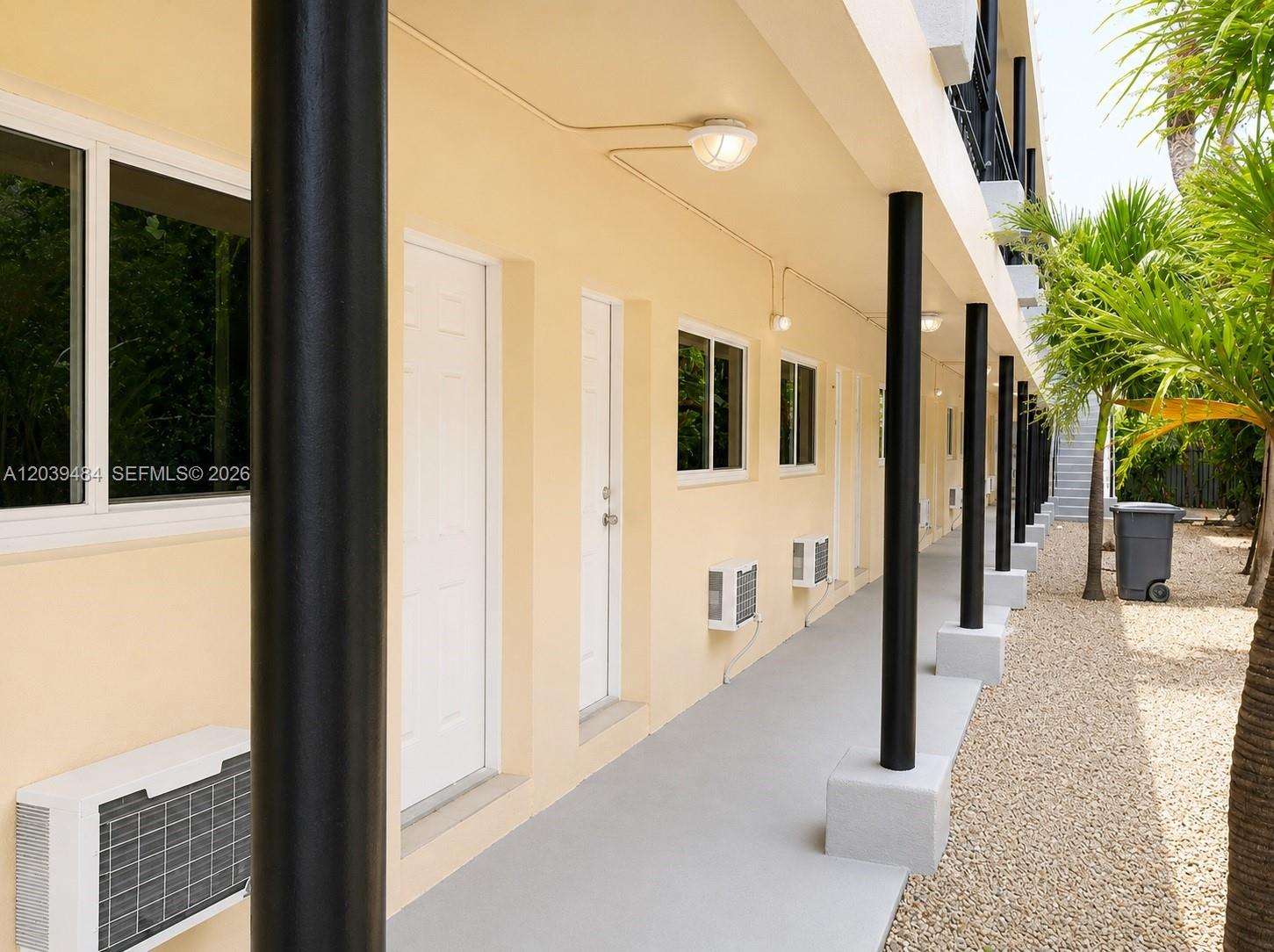 An exterior walkway with black support columns runs along the side of a beige building — 223 NW 12th St # 4, Miami FL 33136, MIAMI, FL