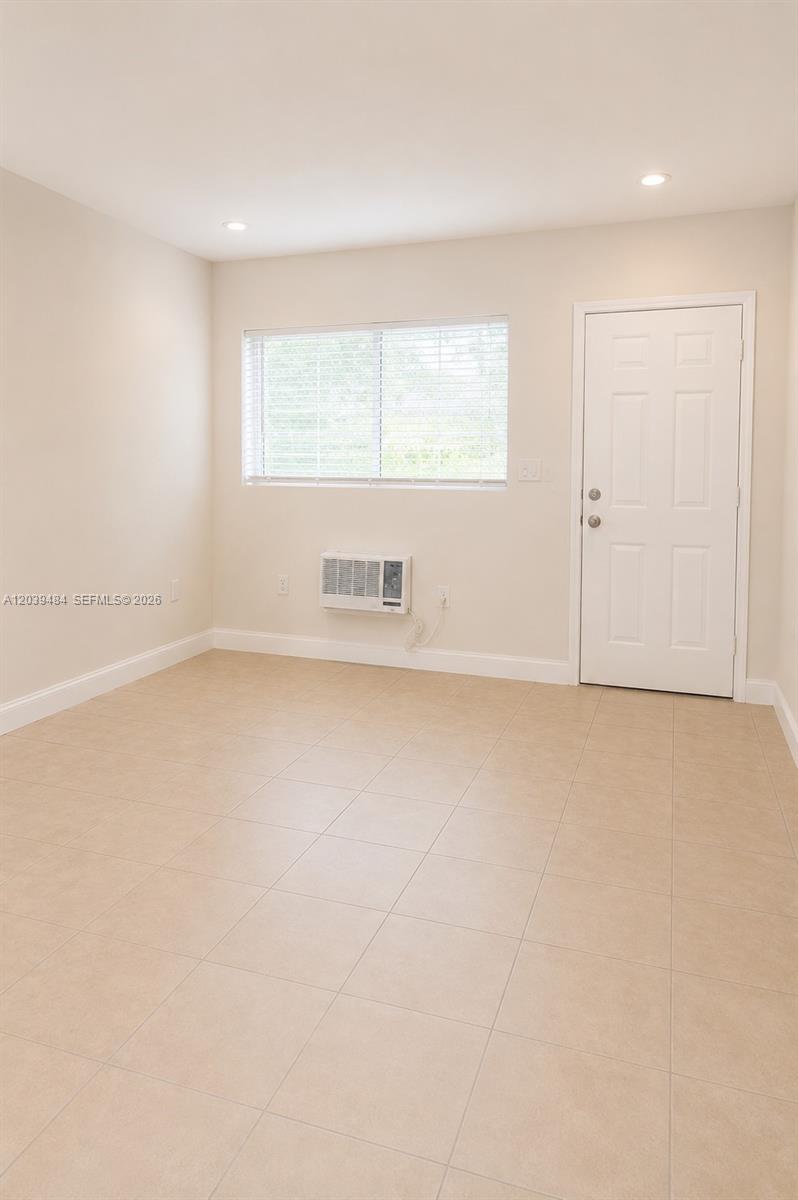 This room features light-colored tile flooring, a window with blinds, and a wall-mounted air conditioner — 223 NW 12th St # 4, Miami FL 33136, MIAMI, FL