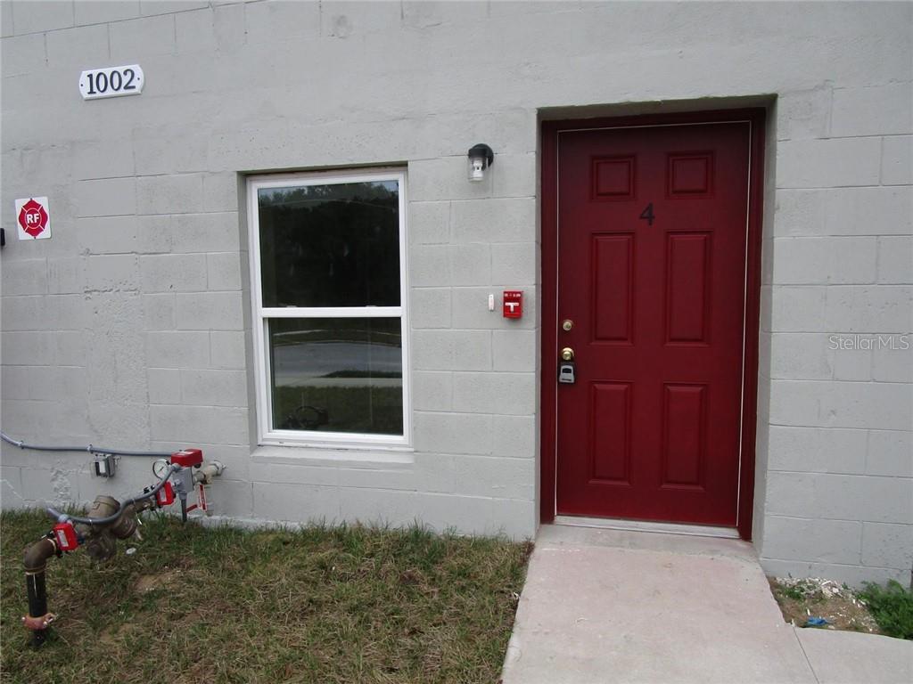 An exterior view of a building featuring a red door labeled four and a window — 1002 E MCDONALD AVENUE UNIT 4, EUSTIS, FL