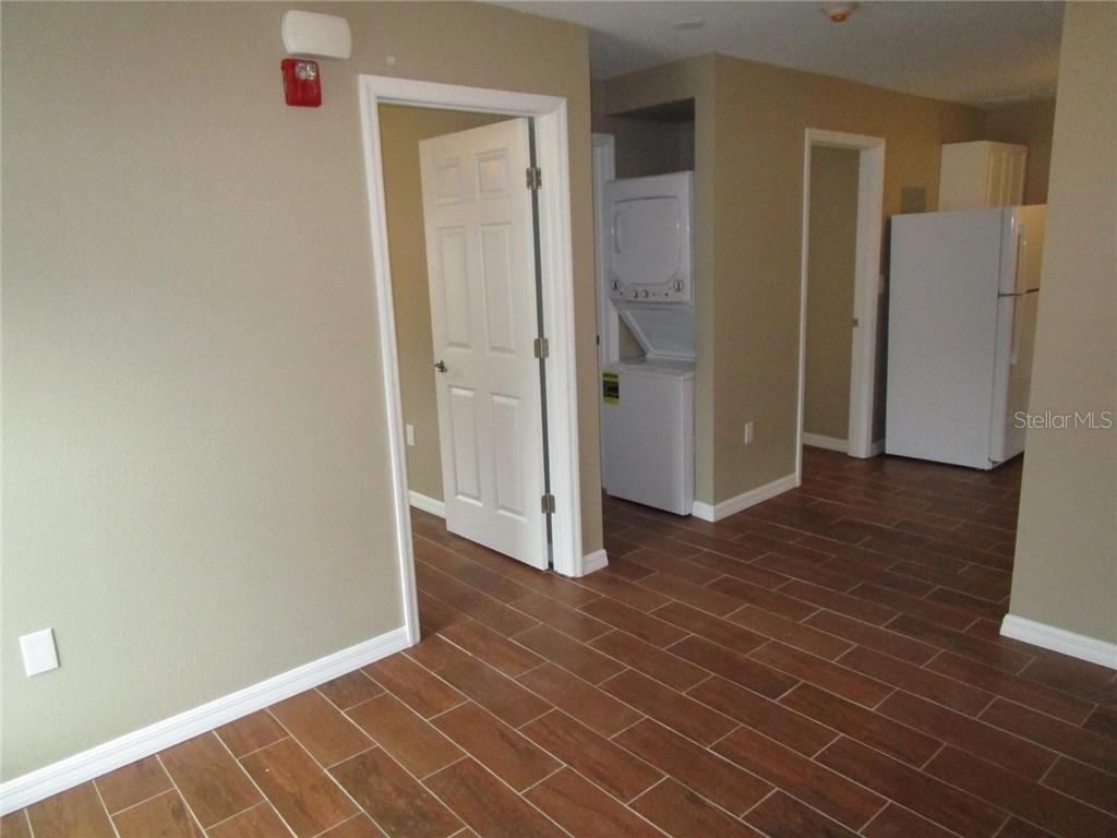 An interior view shows a room with wood-look tile flooring, a laundry closet, and appliances — 1002 E MCDONALD AVENUE UNIT 4, EUSTIS, FL