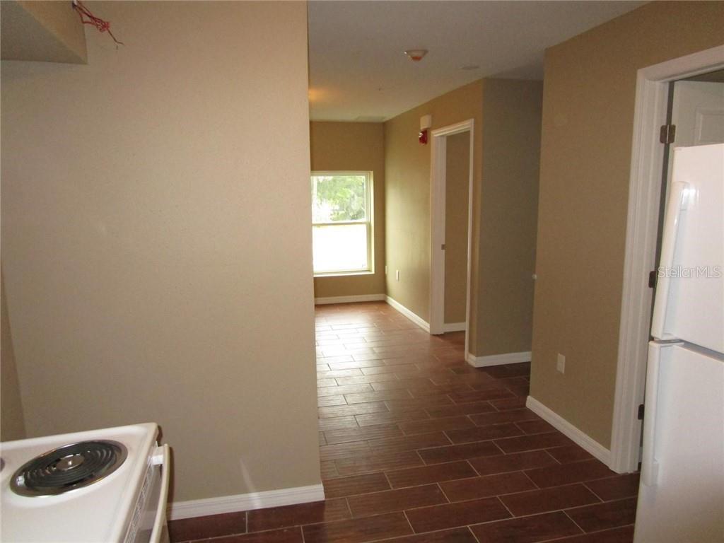 A kitchen area with wood-look tile flooring leads into a hallway with a window — 1002 E MCDONALD AVENUE UNIT 4, EUSTIS, FL