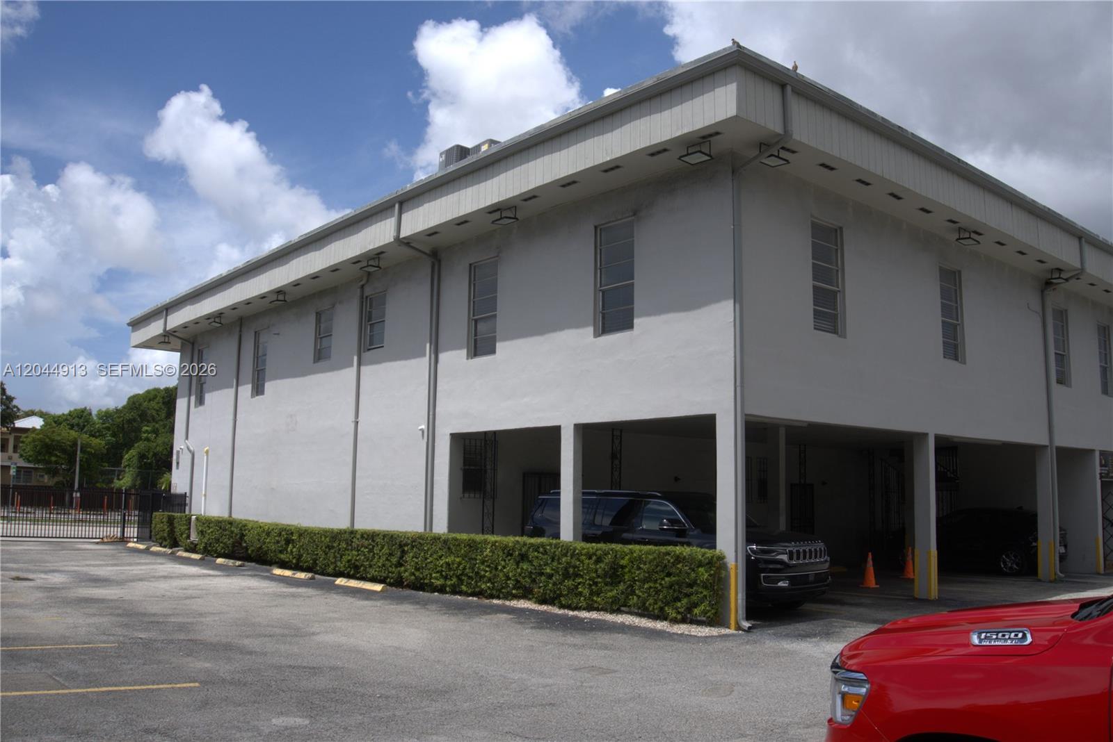 A two-story gray commercial building features a covered ground-level parking area and a hedge — 2433 NW 7th St, Miami FL 33125, MIAMI, FL