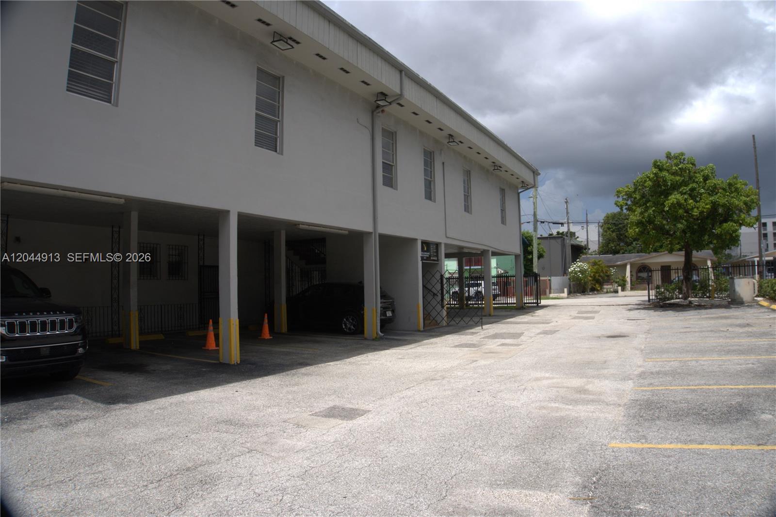 The exterior of a two-story building features a ground-level covered parking area and asphalt lot — 2433 NW 7th St, Miami FL 33125, MIAMI, FL