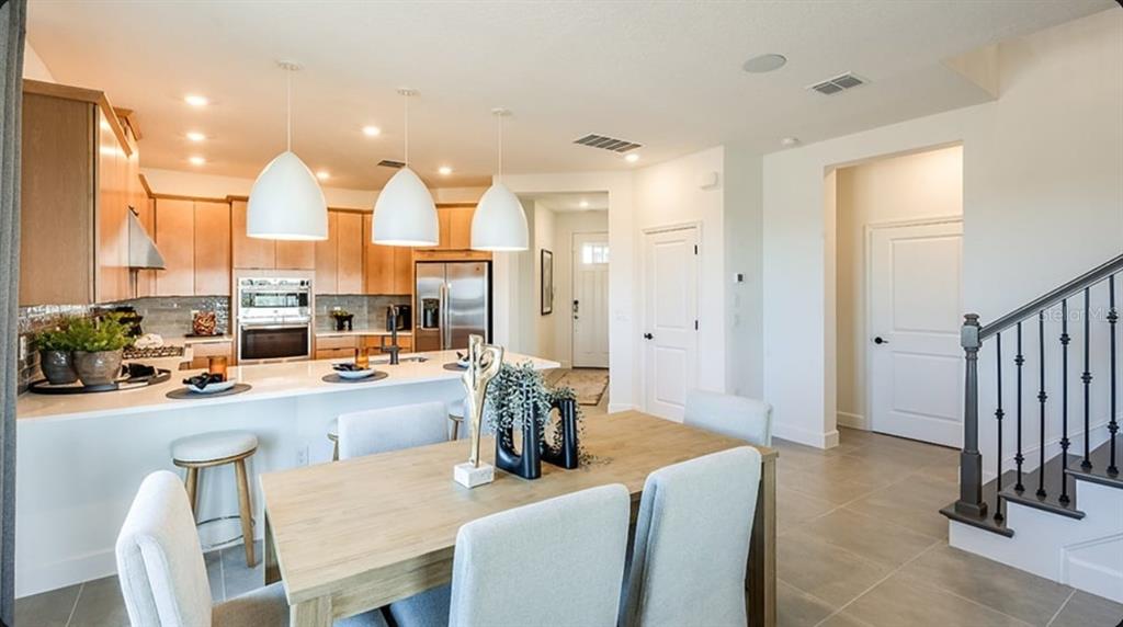 A kitchen with light wood cabinets and a dining area with a wooden table — 32481 SEA LOCH LOOP, MOUNT DORA, FL