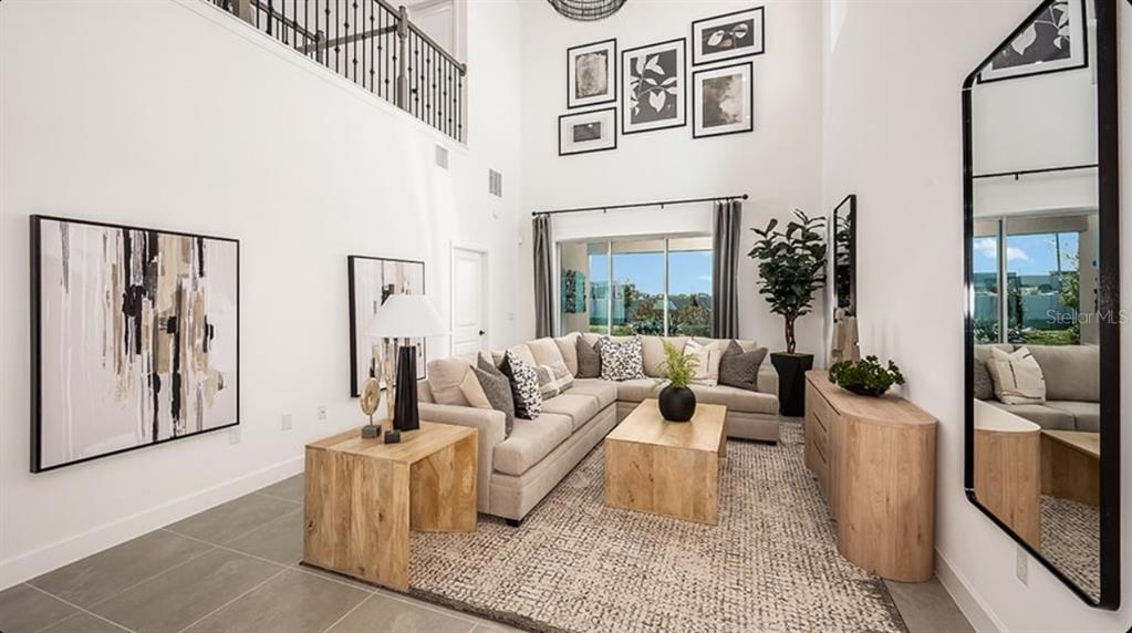 A high-ceilinged living room features a beige sectional sofa, wood furniture, and a large mirror — 32481 SEA LOCH LOOP, MOUNT DORA, FL