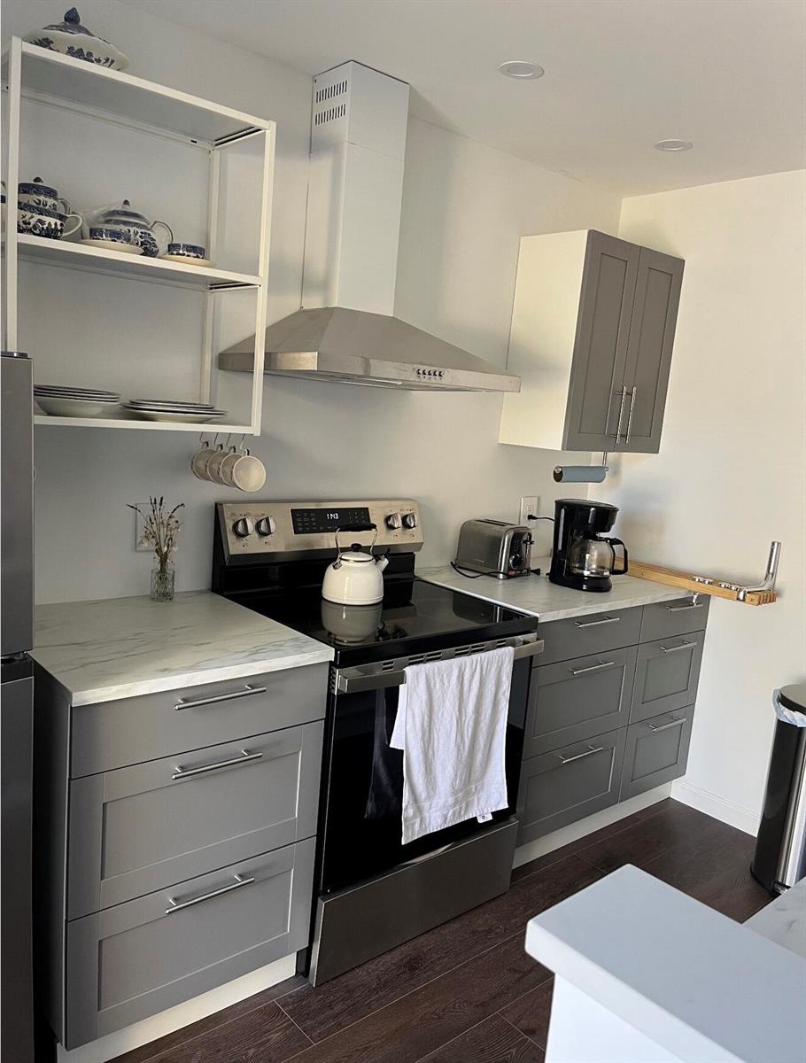 A kitchen features gray cabinets, white marble-look countertops, a stainless steel stove, and open shelving — 2905 29th Way, West Palm Beach FL 33407, WEST PALM BEACH, FL