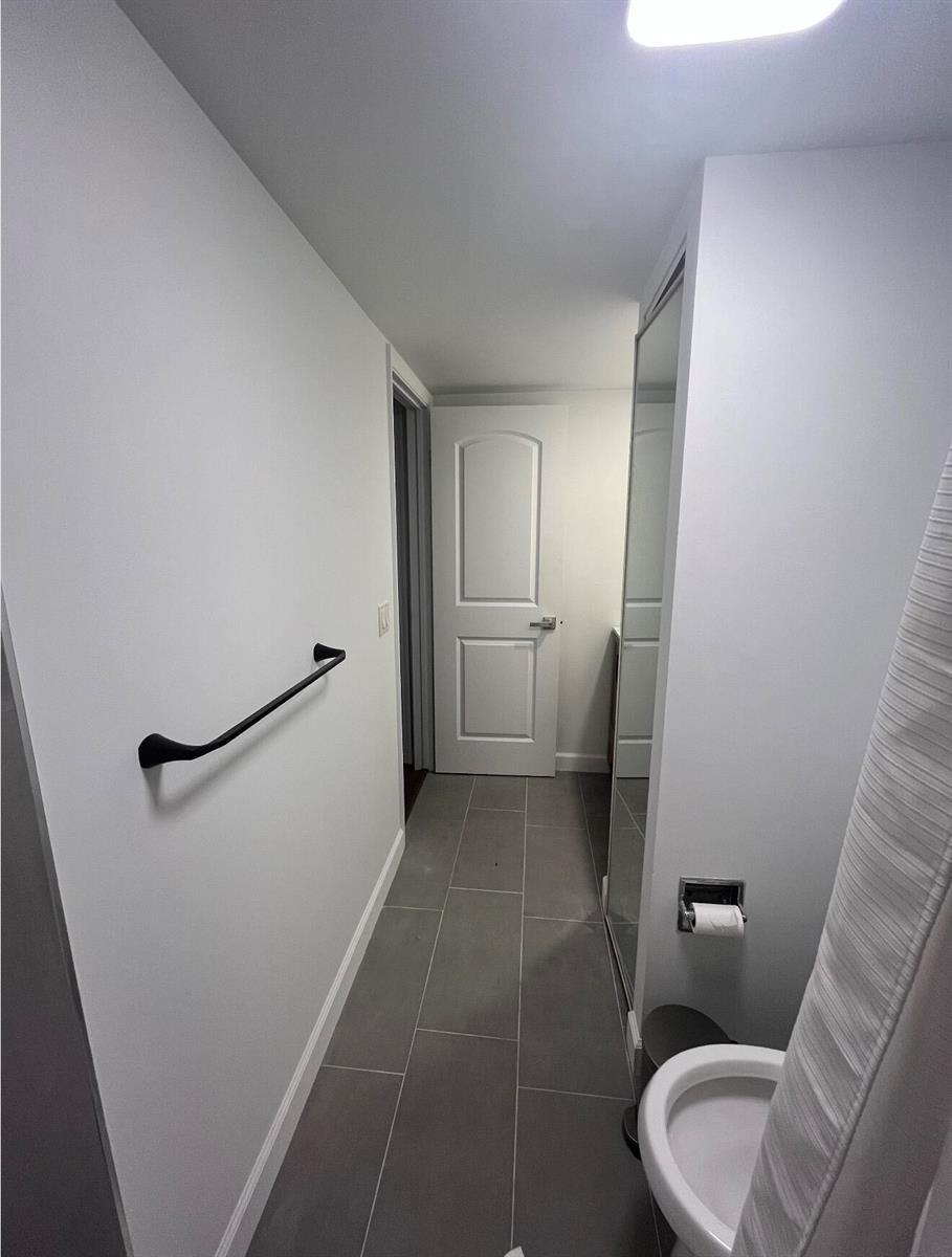 A bathroom features gray tile flooring, a white door, a towel bar, and a mirror — 2905 29th Way, West Palm Beach FL 33407, WEST PALM BEACH, FL