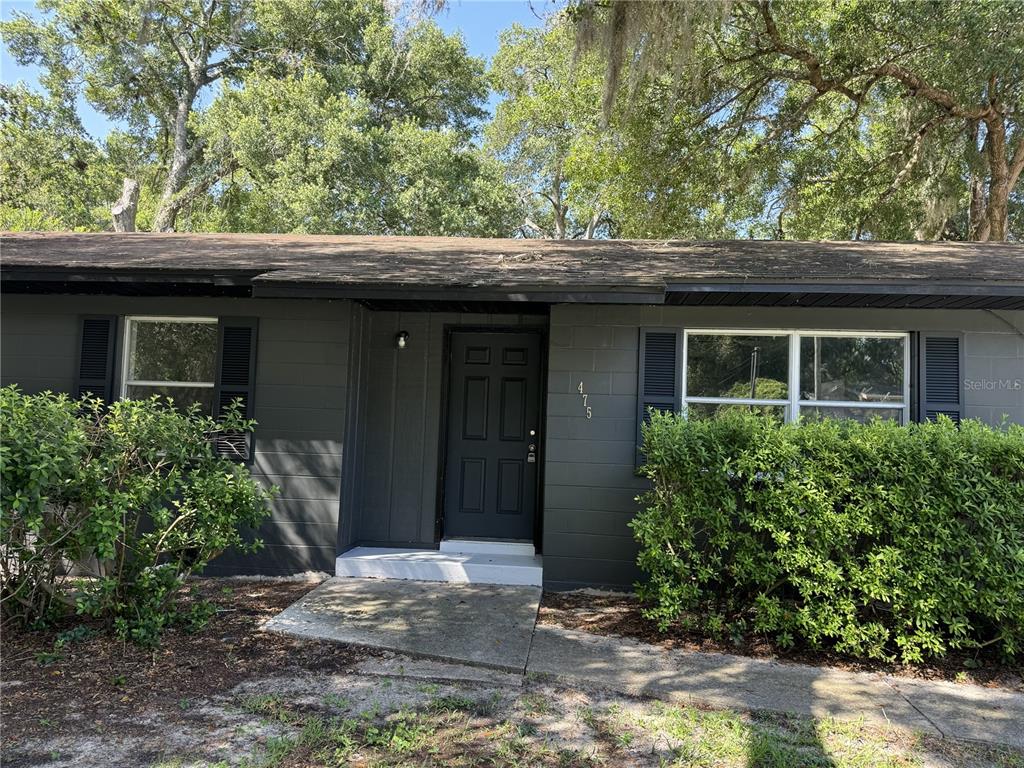 A dark gray, single-story house features a front door, two windows with shutters, and landscaping — 475 SW NIGHTINGALE STREET, KEYSTONE HEIGHTS, FL