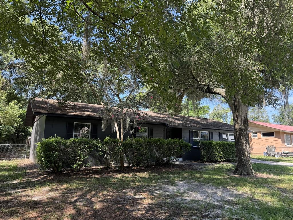 A single-story house with dark gray siding and a large tree in the front yard — 475 SW NIGHTINGALE STREET, KEYSTONE HEIGHTS, FL