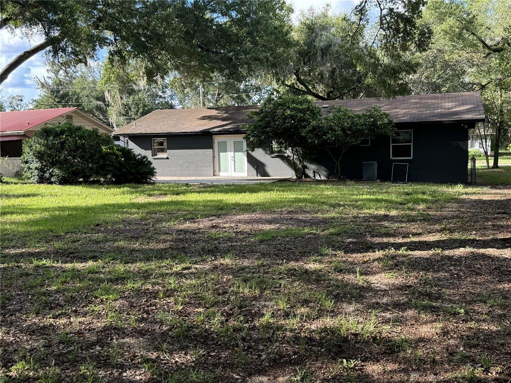 The exterior of a dark-painted, single-story house with a yard and mature trees — 475 SW NIGHTINGALE STREET, KEYSTONE HEIGHTS, FL
