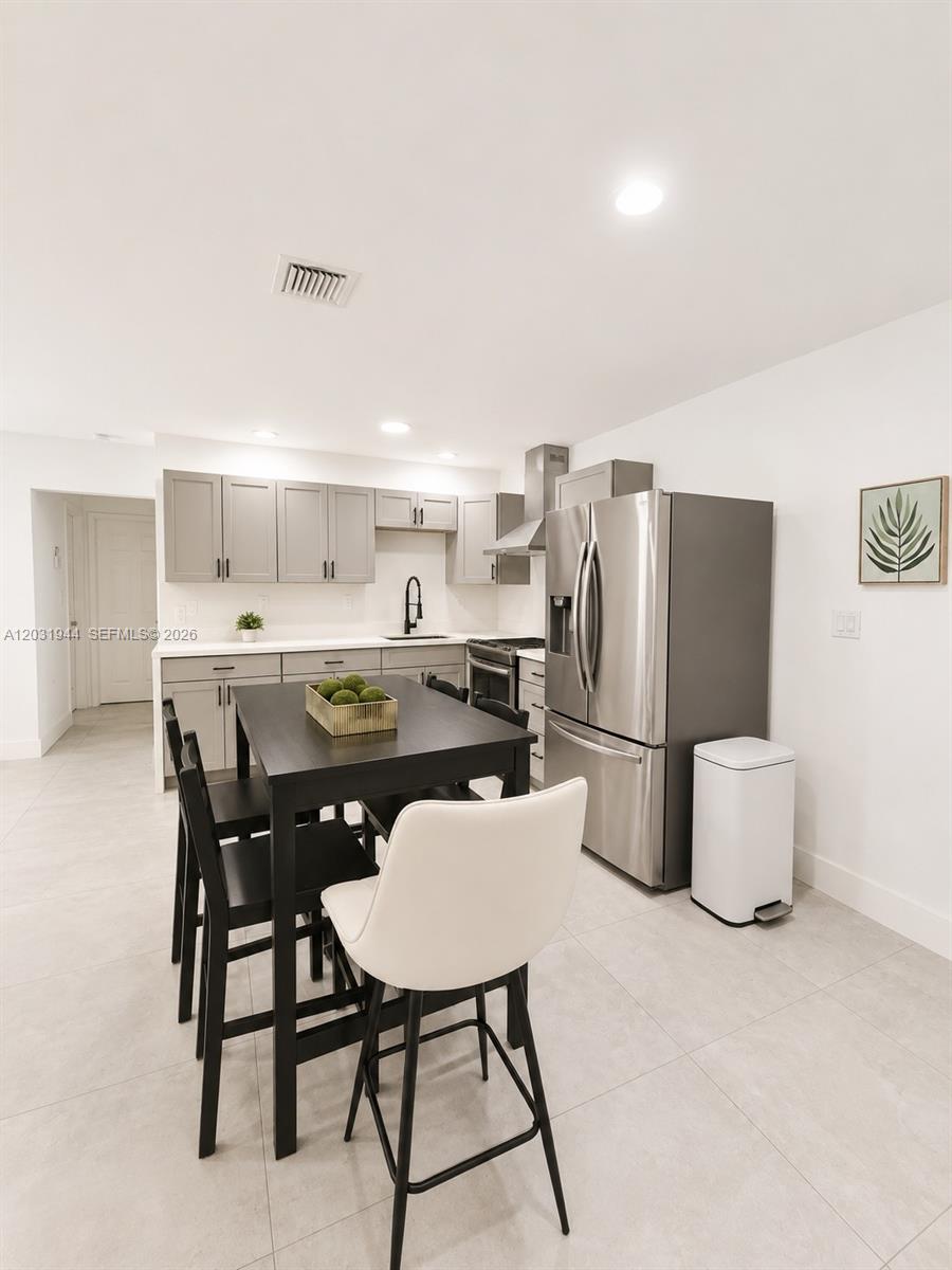 A modern kitchen features gray cabinets, stainless steel appliances, and a black dining table — 800 NE 2nd Ct, Hallandale Beach FL 33009, HALLANDALE BEACH, FL
