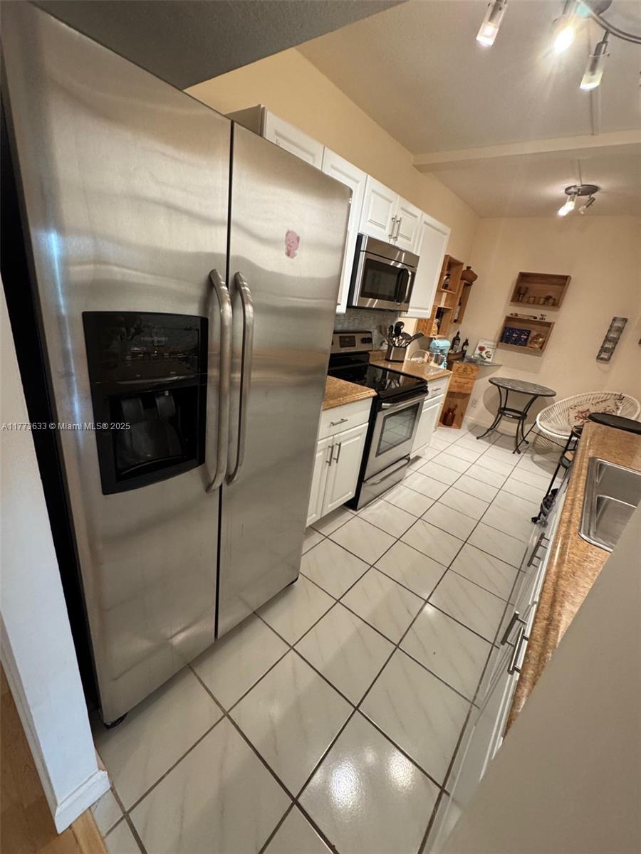 A narrow kitchen features stainless steel appliances, white cabinets, and light-colored tile flooring — 4330 Hillcrest Dr # 304, Hollywood FL 33021, HOLLYWOOD, FL