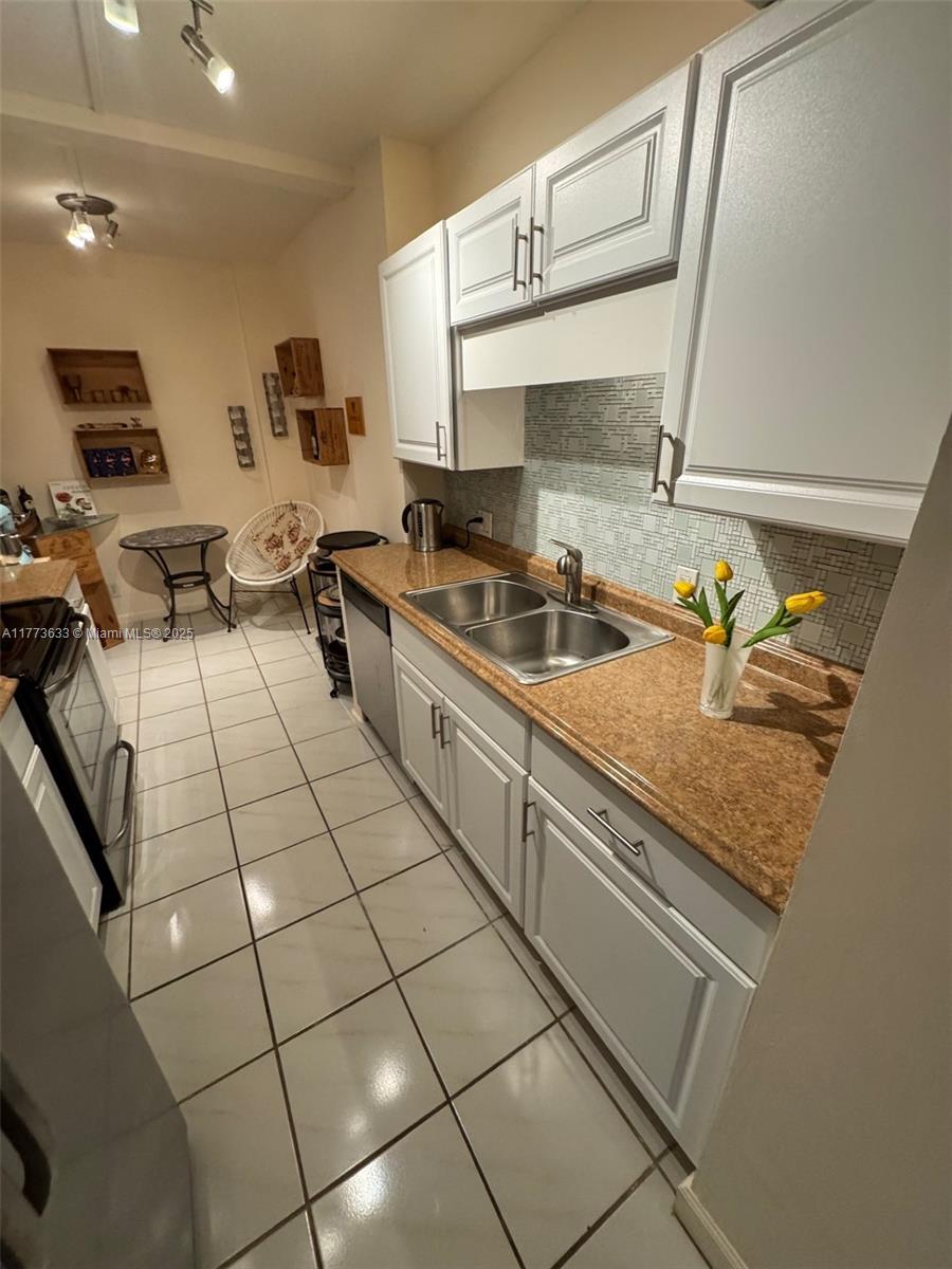 A galley kitchen features white cabinets, a brown speckled countertop, and a small dining area — 4330 Hillcrest Dr # 304, Hollywood FL 33021, HOLLYWOOD, FL