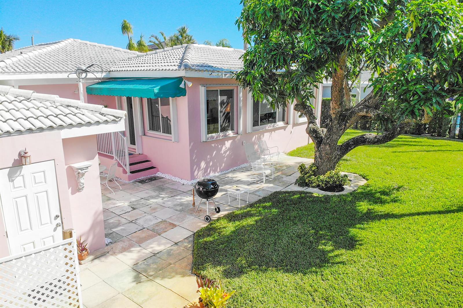 A pink house with a tiled patio, a large tree, and a green lawn — 3216 Karen Drive, Delray Beach FL 33483, DELRAY BEACH, FL