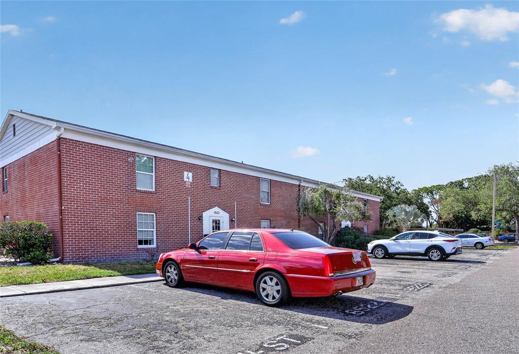 A red sedan is parked in front of a two-story brick apartment building — 8542 10TH STREET N UNIT B, ST PETERSBURG, FL