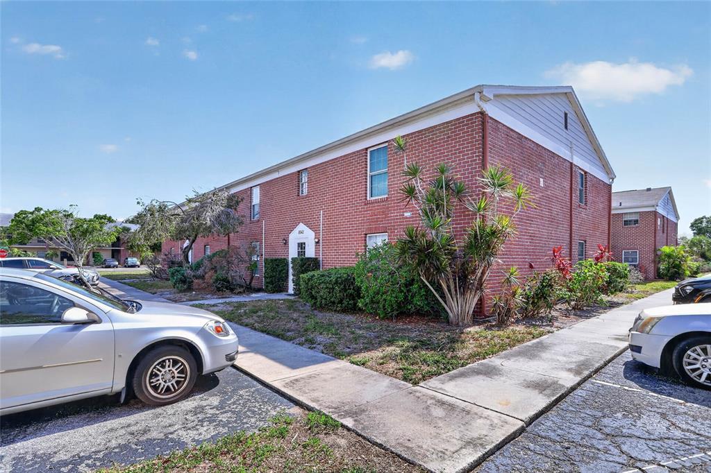 A two-story brick apartment building with a sidewalk and parked cars in front — 8542 10TH STREET N UNIT B, ST PETERSBURG, FL