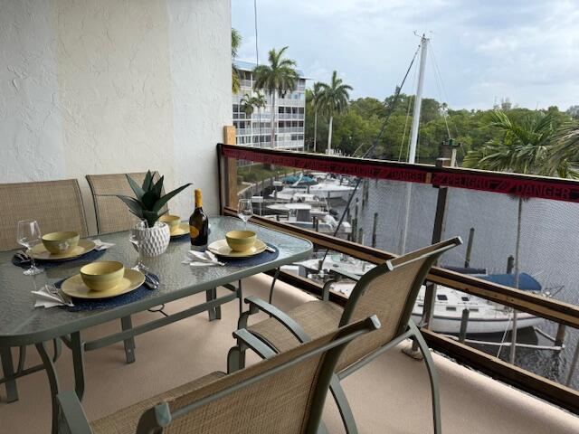 A balcony dining set overlooks a marina with boats and palm trees — 1319 E Hillsboro Boulevard # 412, Deerfield Beach FL 33441, DEERFIELD BEACH, FL