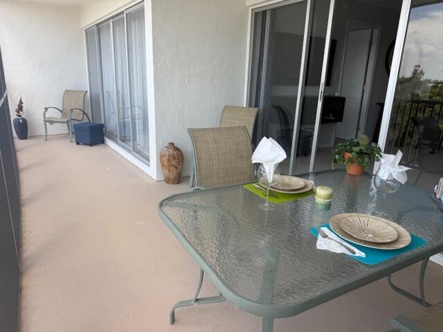 A glass-topped dining table sits on a balcony with sliding glass doors and outdoor chairs — 1319 E Hillsboro Boulevard # 412, Deerfield Beach FL 33441, DEERFIELD BEACH, FL