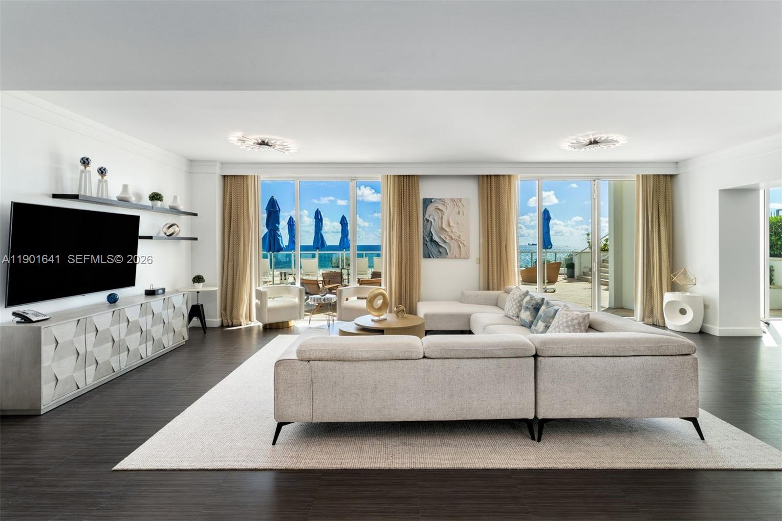 A spacious living room features a large sectional sofa, media console, and floor-to-ceiling balcony doors — 4391 Collins Ave # 512, Miami Beach FL 33140, MIAMI BEACH, FL
