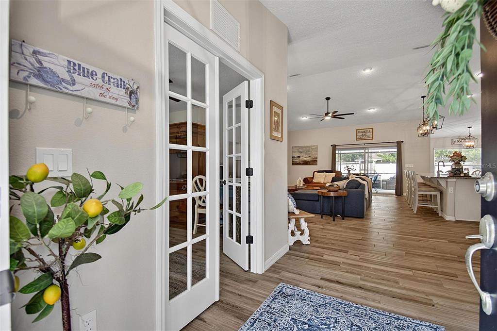 A view from an entryway into an open-concept living room and kitchen with wood flooring — 73 LINDSAY DRIVE, PALM COAST, FL