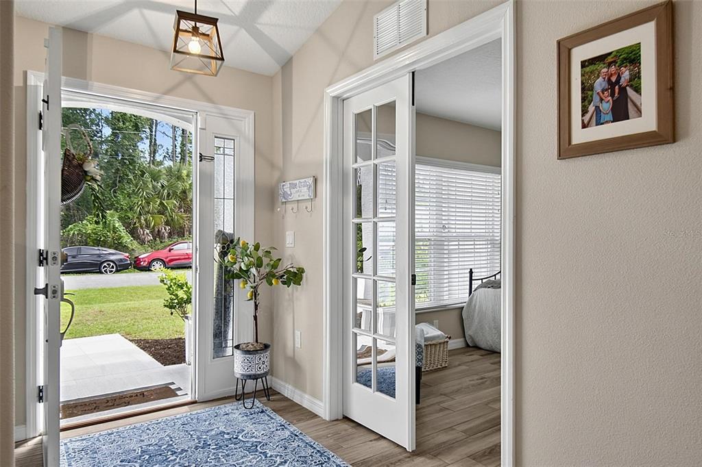 An entryway features a blue patterned rug, a potted lemon tree, and French doors — 73 LINDSAY DRIVE, PALM COAST, FL