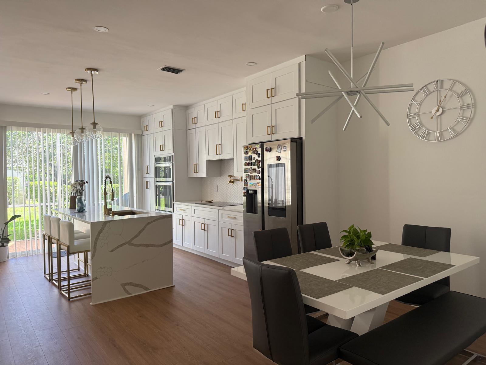 A modern kitchen and dining area featuring white cabinetry, a marble island, and wood flooring — 6772 Via Regina, Boca Raton FL 33433, BOCA RATON, FL