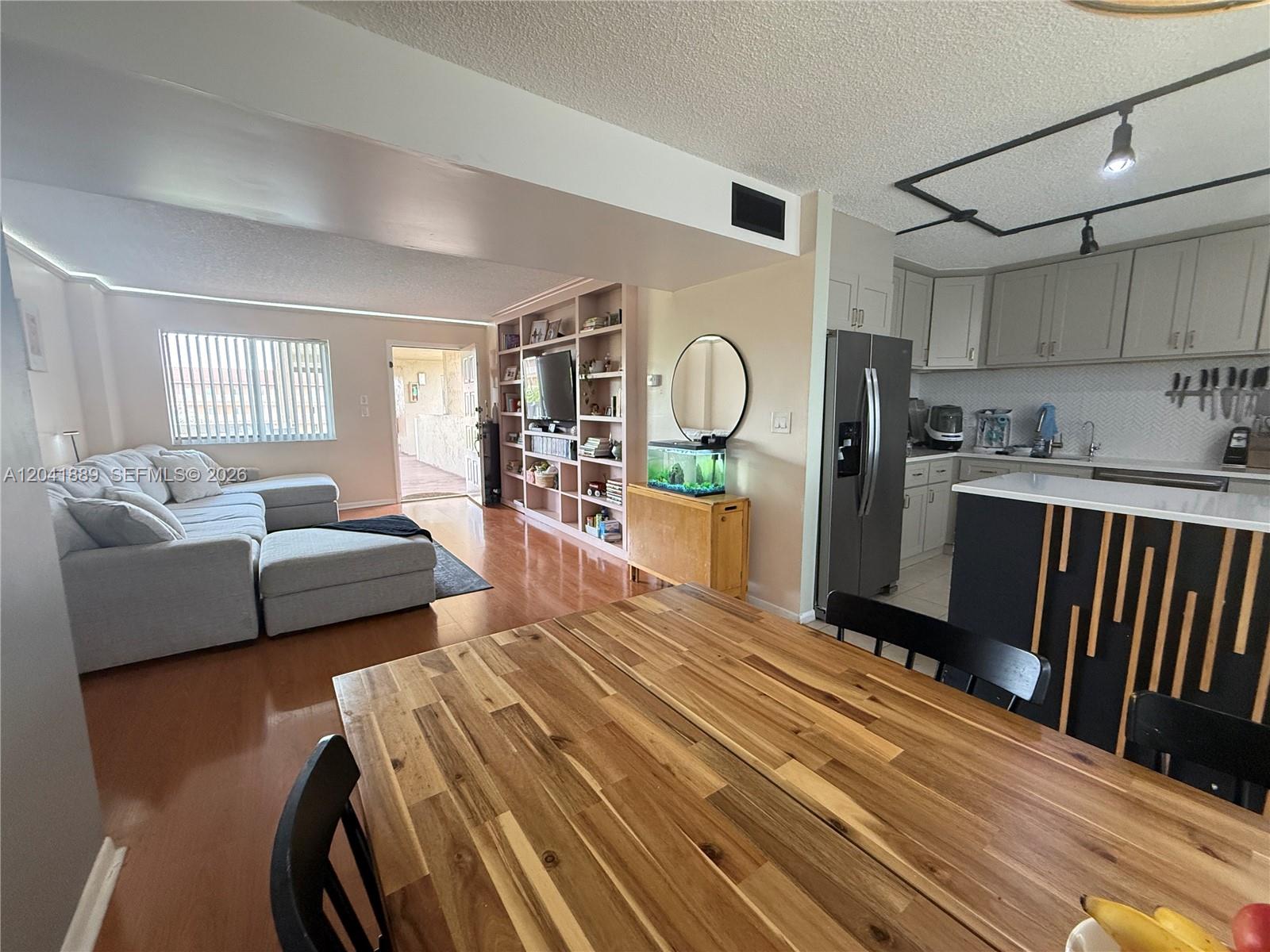 An open-concept living area features a kitchen with grey cabinets, a dining table, and shelving — 17000 NW 67th Ave # 402, Hialeah FL 33015, HIALEAH, FL