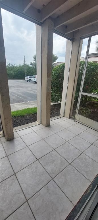 A tiled screened-in porch overlooks a parking lot with a green hedge and trees — 546 ORANGE DRIVE UNIT 13, ALTAMONTE SPRINGS, FL