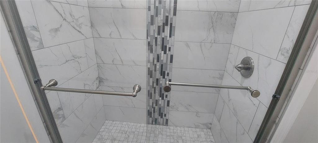 A walk-in shower features white marble-look wall tiles, a vertical mosaic accent strip, and glass doors — 546 ORANGE DRIVE UNIT 13, ALTAMONTE SPRINGS, FL