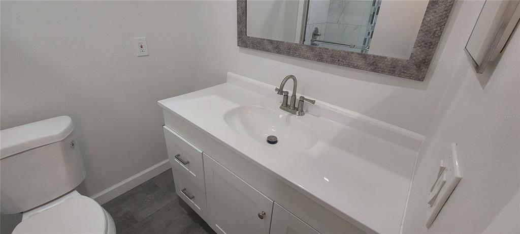 A bathroom features a white vanity with a sink, a toilet, and a framed mirror — 546 ORANGE DRIVE UNIT 13, ALTAMONTE SPRINGS, FL