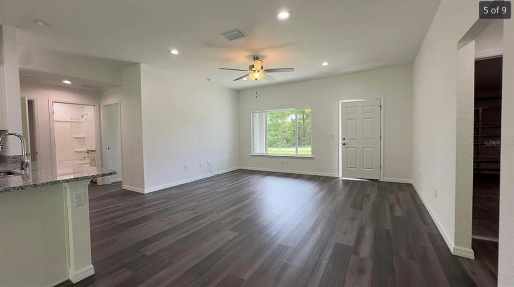 An open-concept living area features dark wood-look flooring, white walls, recessed lighting, and a ceiling fan — 122 MALAUKA LOOP, OCKLAWAHA, FL